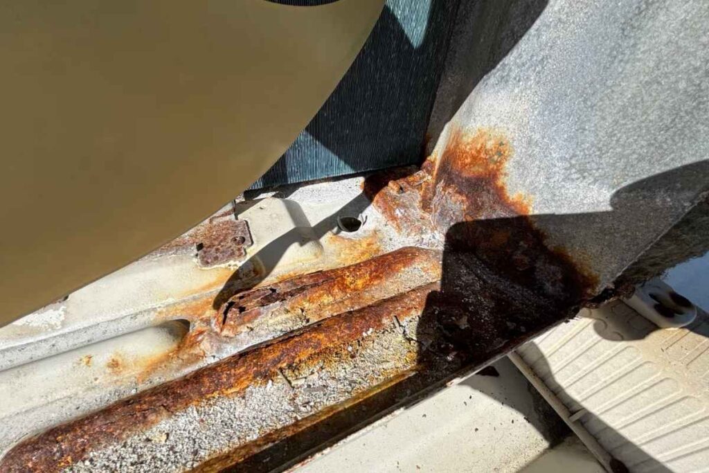 Severe rust and flaking metal on an outdoor unit base pan needing rust treatment air conditioning Gold Coast