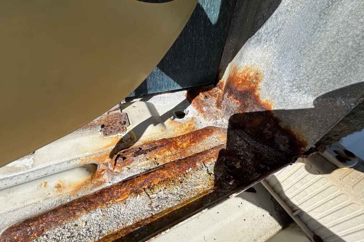 Severe rust and flaking metal on an outdoor unit base pan needing rust treatment air conditioning Gold Coast
