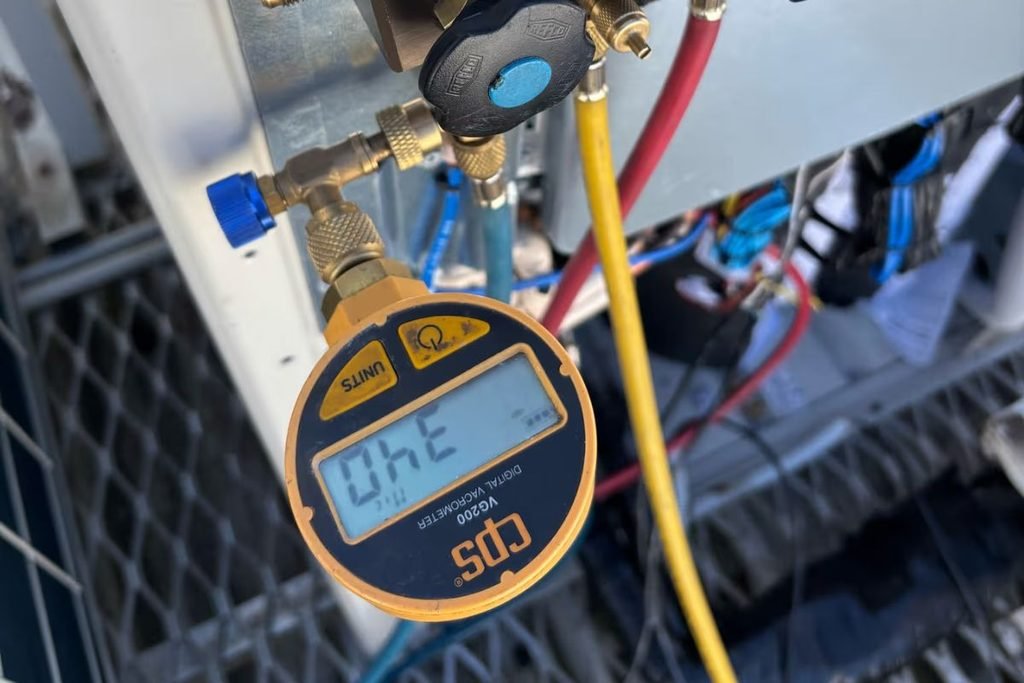 Pre-summer air conditioning service: technician checking gas pressure with a digital gauge